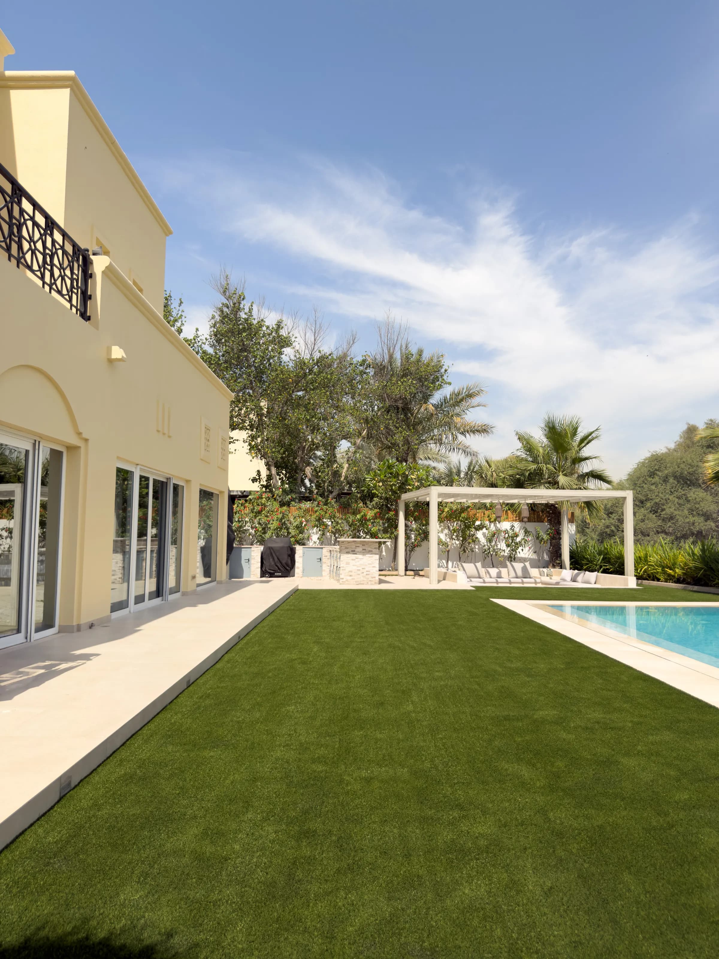 Artificial grass laid between paving and mature planting in a villa garden at Alvorada, Arabian Ranches, Dubai.