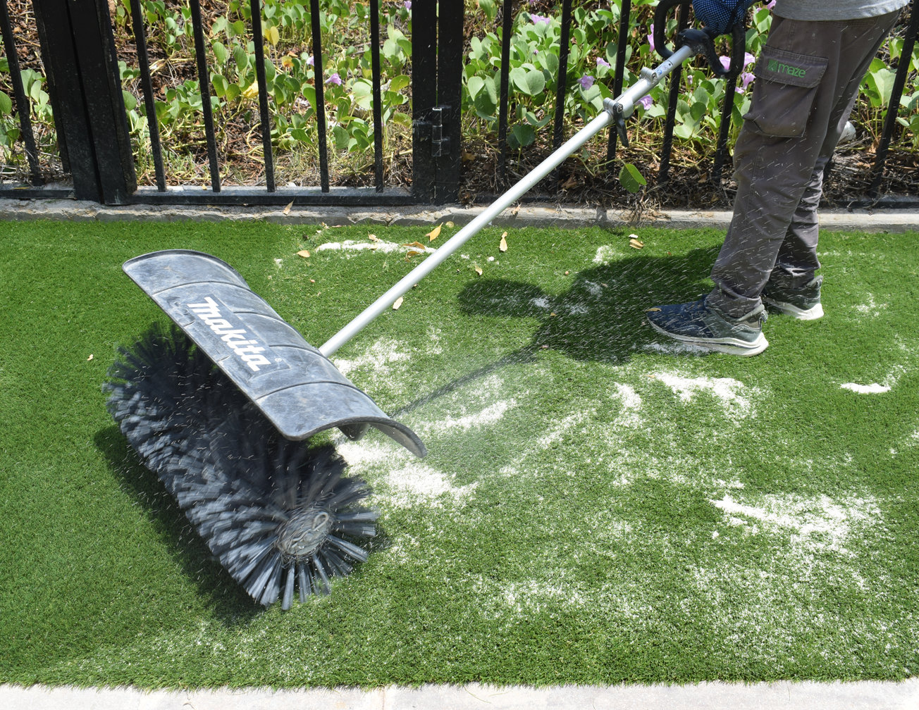A power brush working infill down into the pile of a Mazegrass lawn